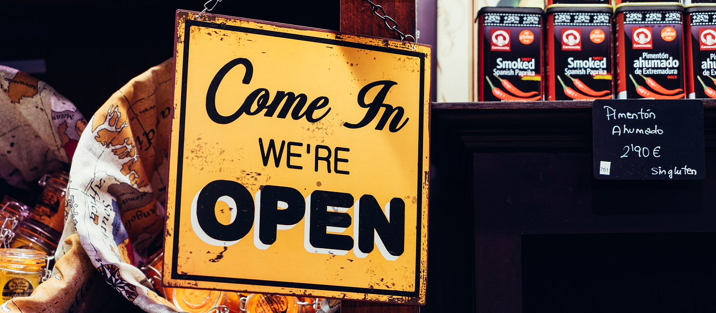 A photo with a shop sign saying “Come in, we’re open”